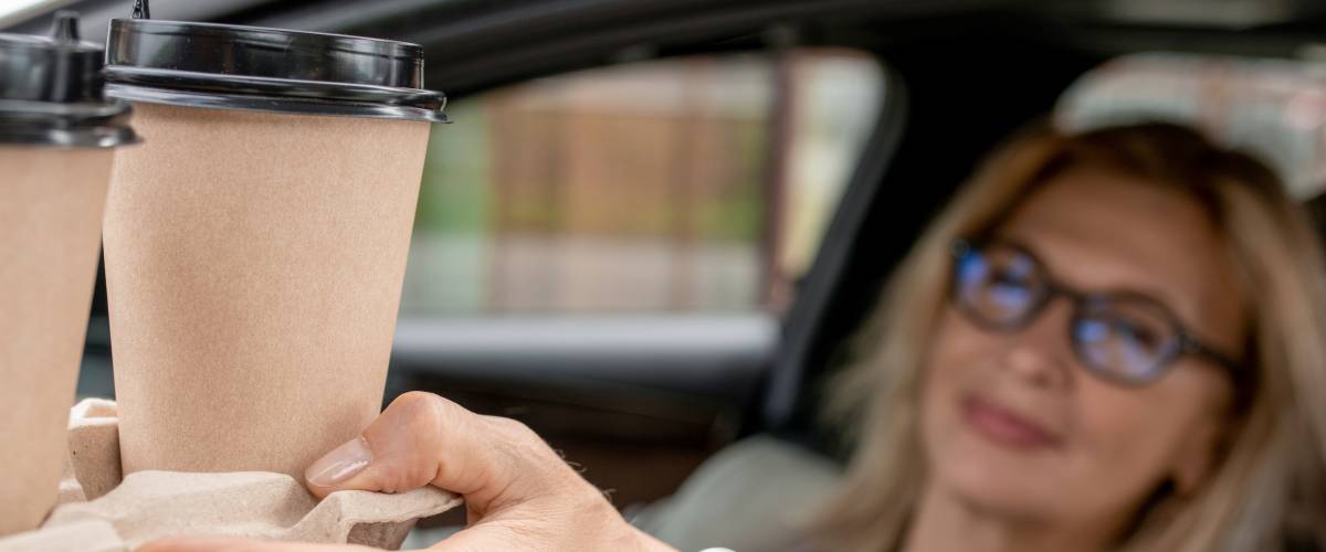 Women accepting coffee in car