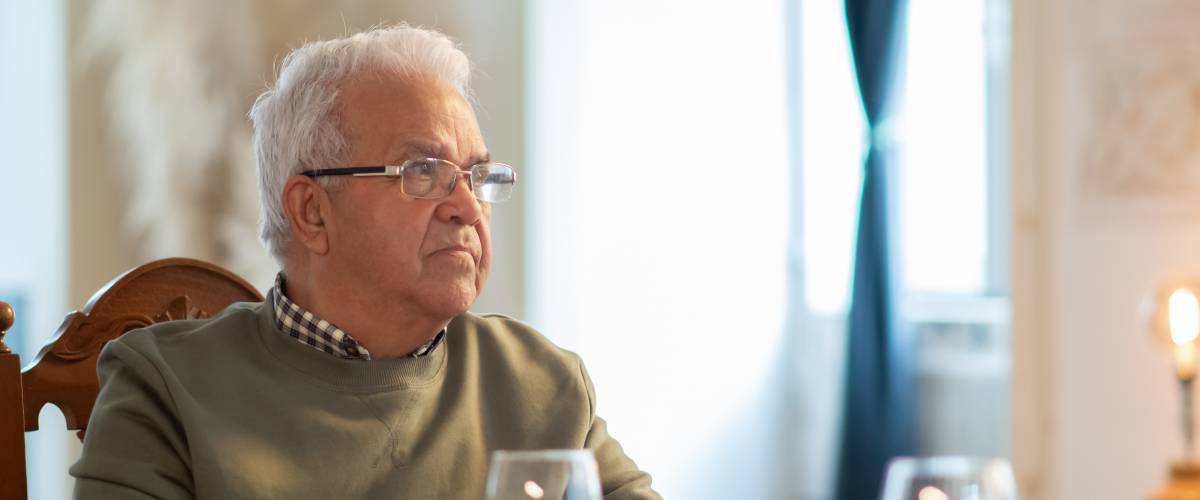 Older gentleman sits at a table in restaurant