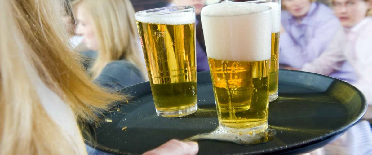 Waitress, bringing a round of beers to a waiting group of customers