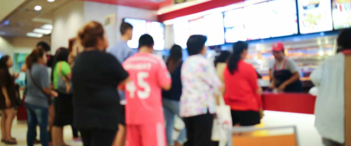 Blurred people queue up waiting in line to buy fast food.