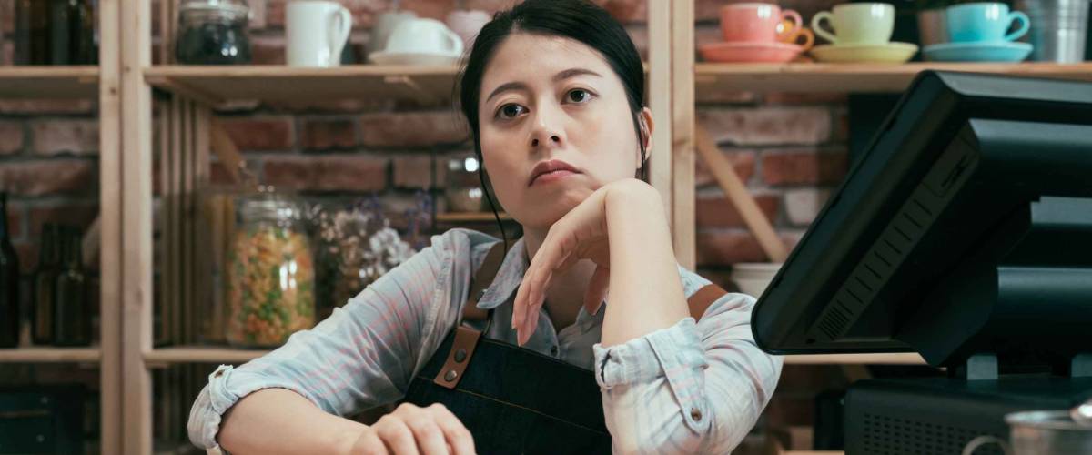 Asian server looking unimpressed behind counter