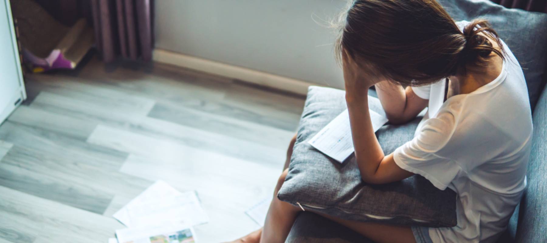 young Caucasian women worried about bills, sitting on couch at home
