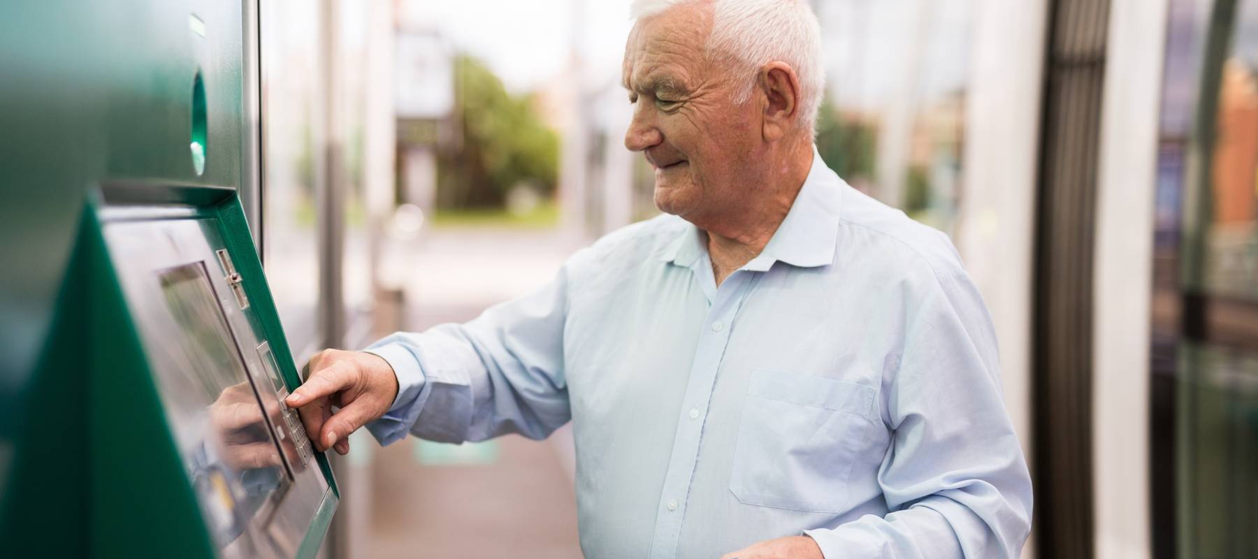 Senior using ATM machine to withdraw his money.