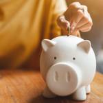 woman hand putting money coin into piggy for saving money wealth and financial concept.