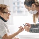 A medical professional takes an elderly woman's blood pressure.