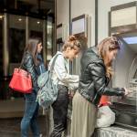 Four friends withdrawing money from ATM.