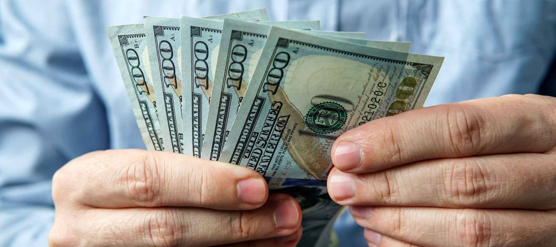 man holding five hundred US dollars.
