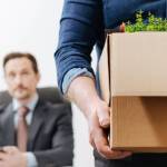 Employee quitting and walking out of office with box