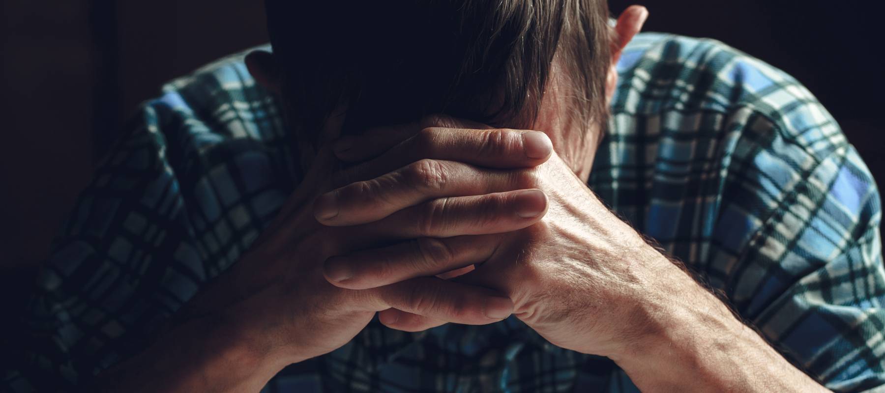 A sad man covers his face with his hands.