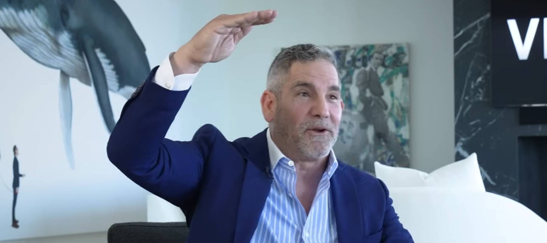 Grant Cardone seen sitting in a living room, gesturing with his hand over his head, speaking.