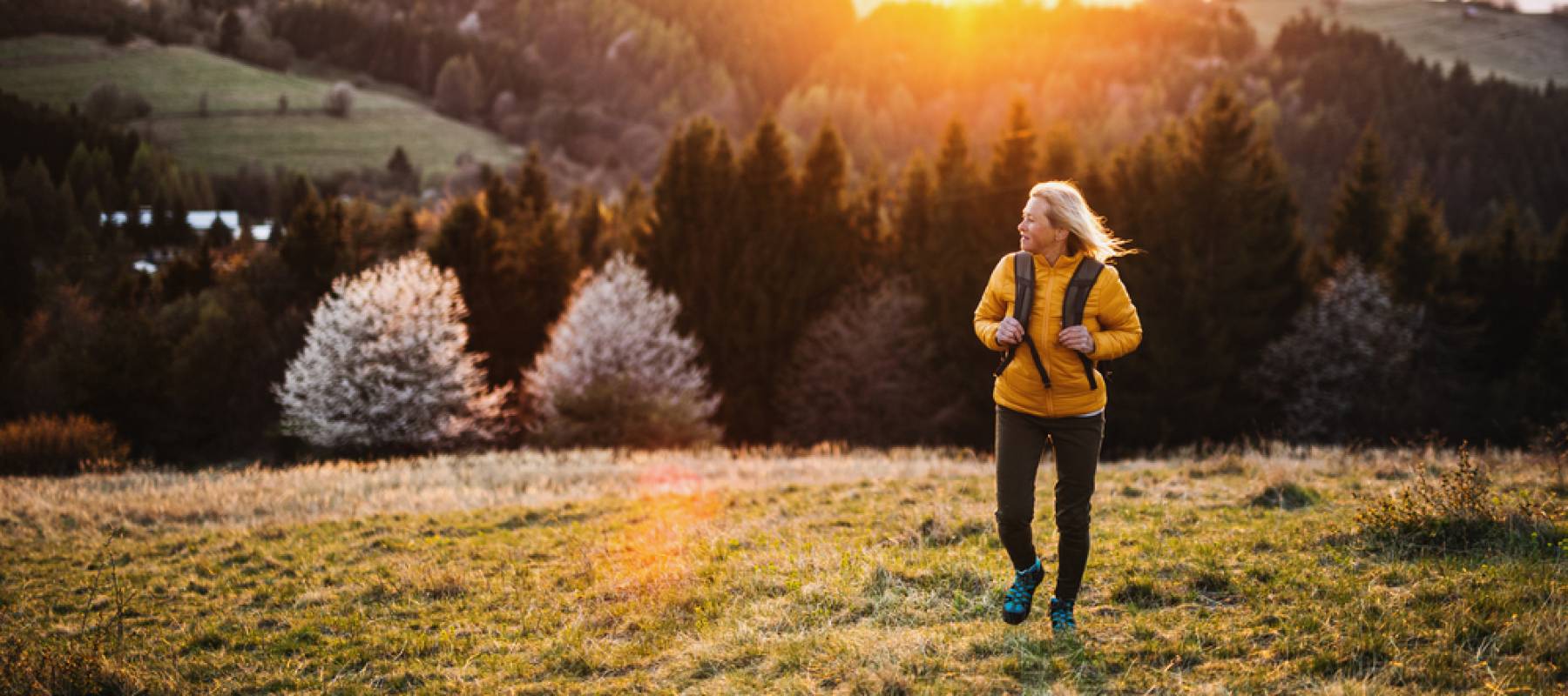 boomer woman hiking, surrounded by hills and trees