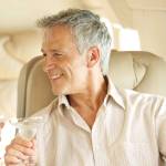 Bonding on a romantic getaway. Smiling and happy couple seated in a private jet and toasting each other.