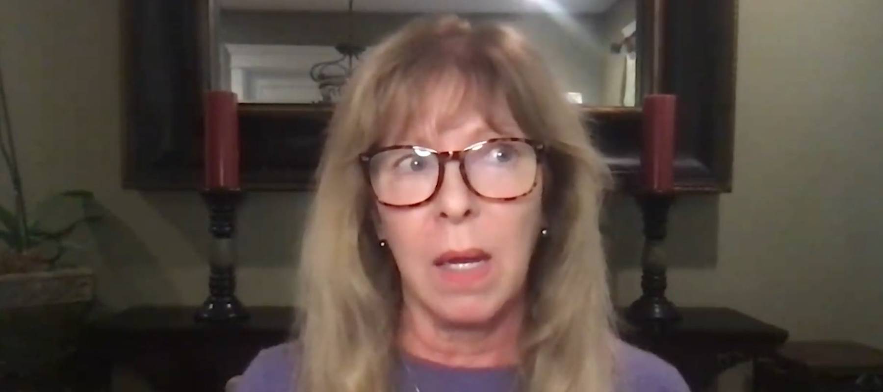 Woman seen sitting in front of computer, looking off to the side of the camera, distressed.