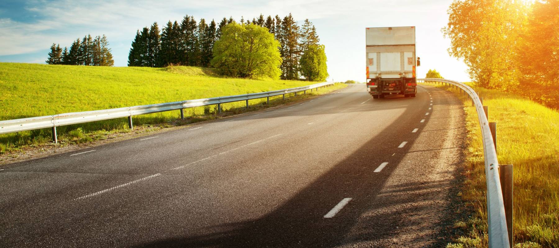 asphalt road on dandelion field with a small truck. lorry moving on sunny evening