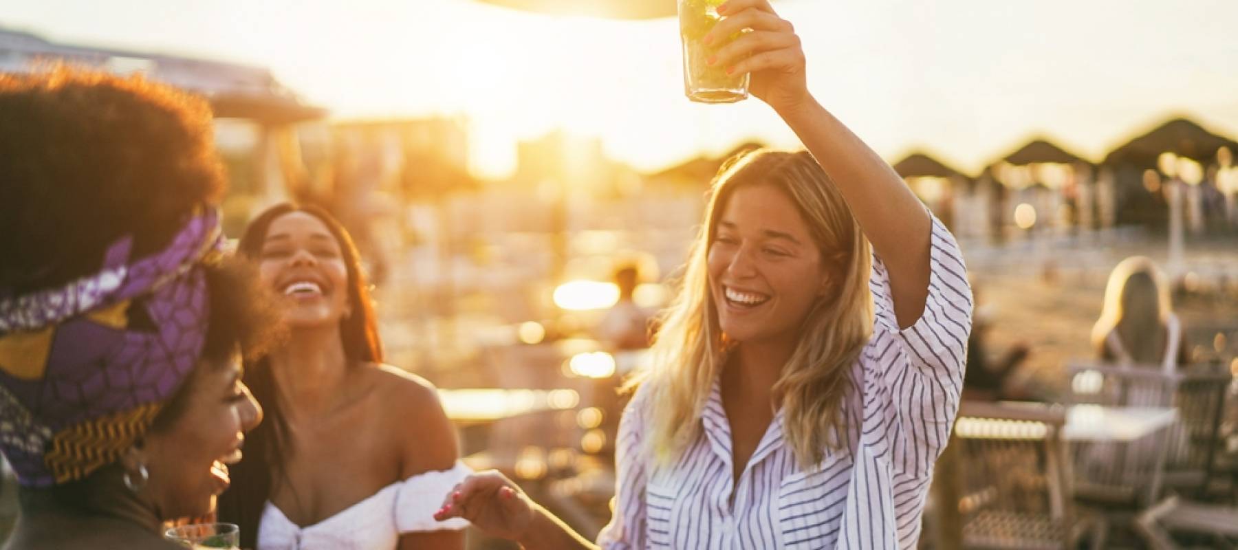 happy women having fun drinking cocktails at bar on the beach