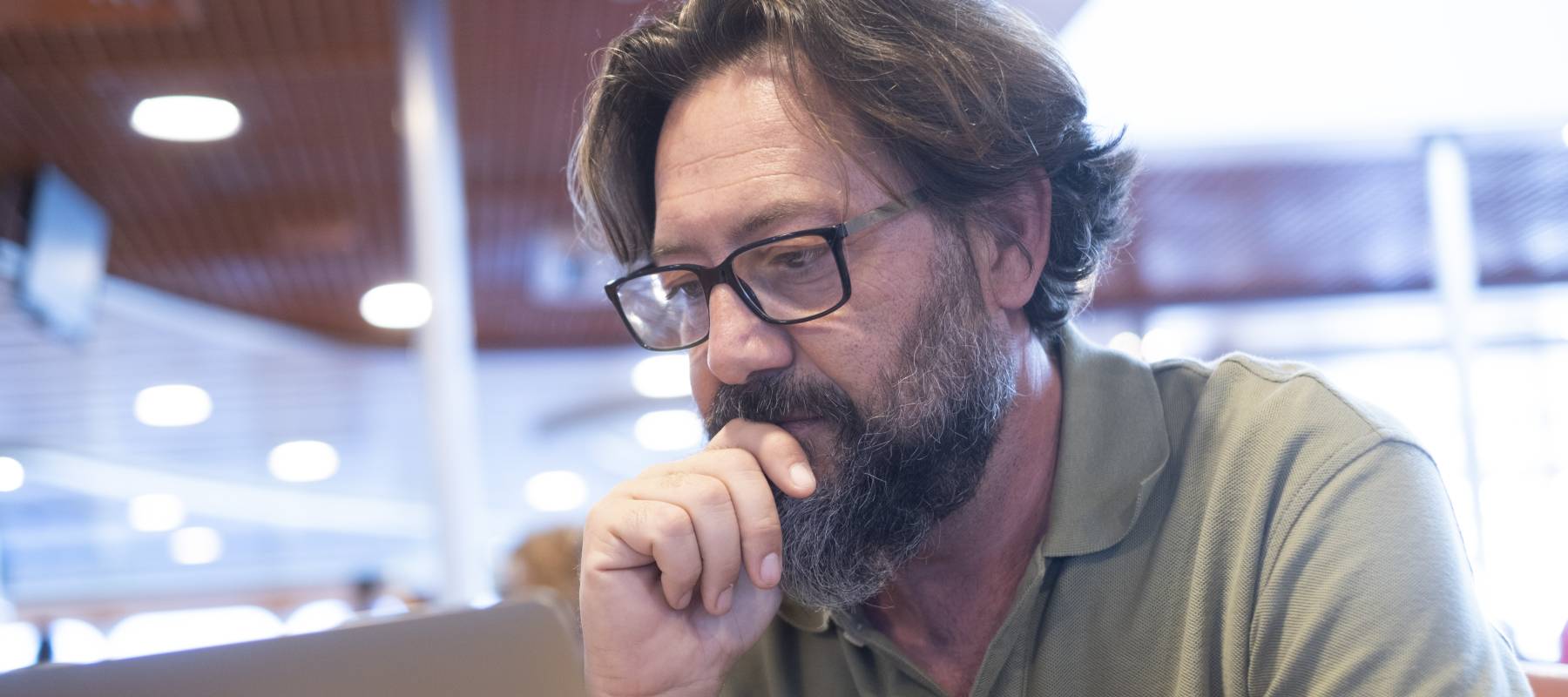 Older man with grey-streaked hair looks with concern at a computer screen.