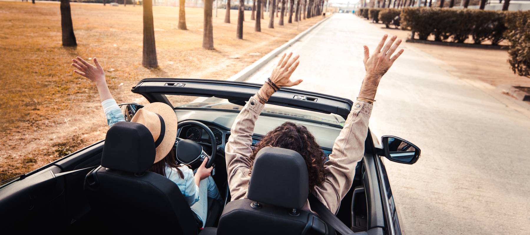 happy couple driving on city street in convertible car