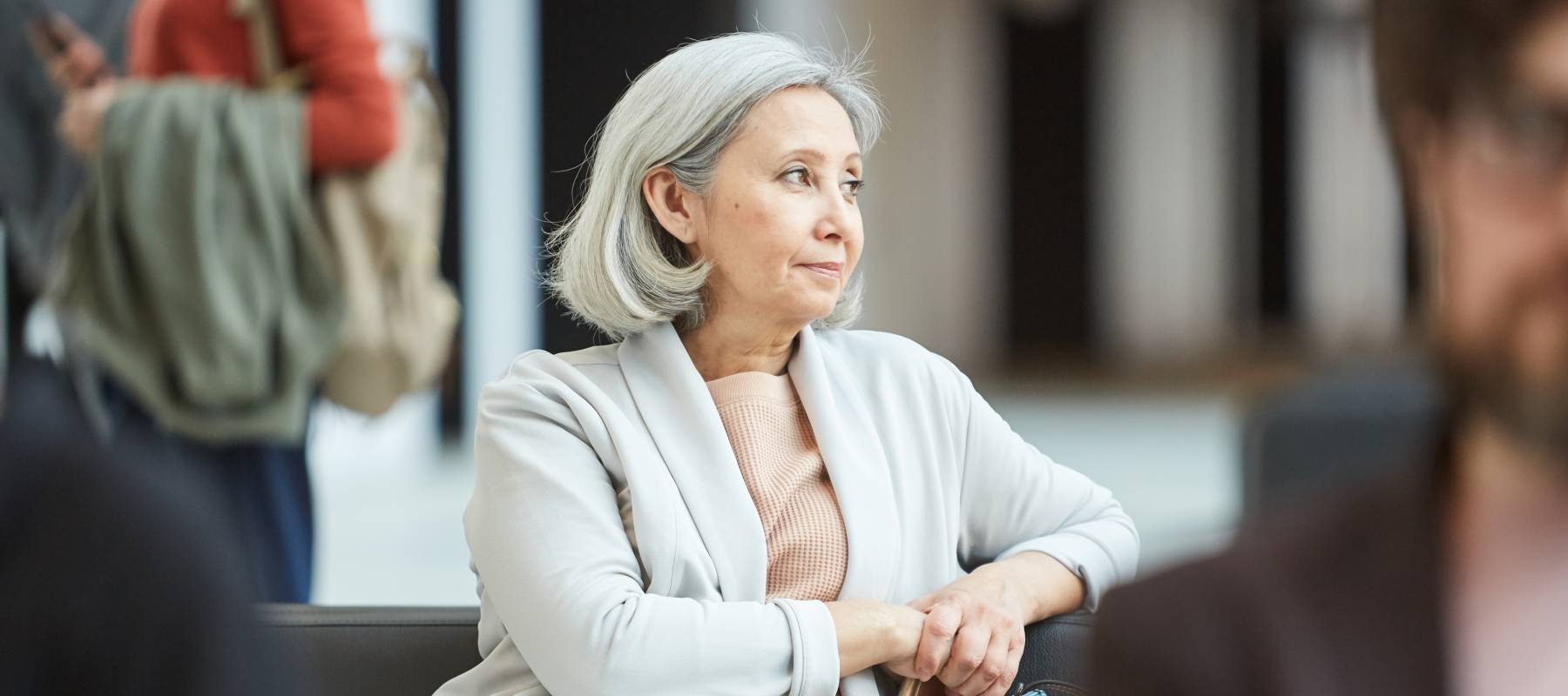 portrait of mature woman with gray hair sitting relaxed in departure lounge looking away