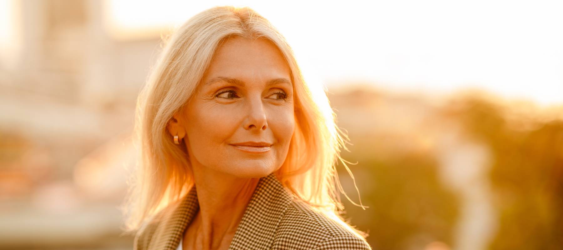mature white businesswoman wearing suit smiling and looking aside outdoors