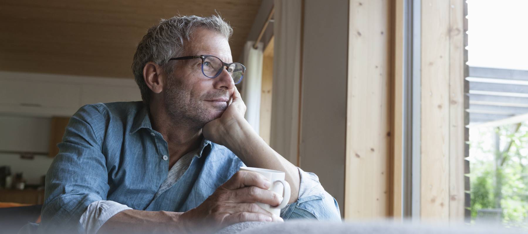 mature man holding cup sitting on couch