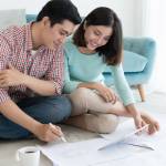Attractive young asian adult couple looking at house plans.