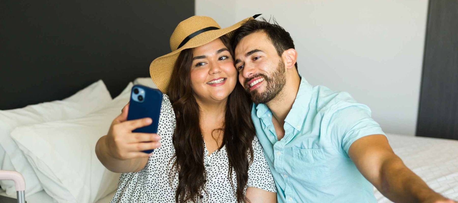 Young couple enjoying a relaxing moment in their hotel room, taking a selfie after returning from a vacation