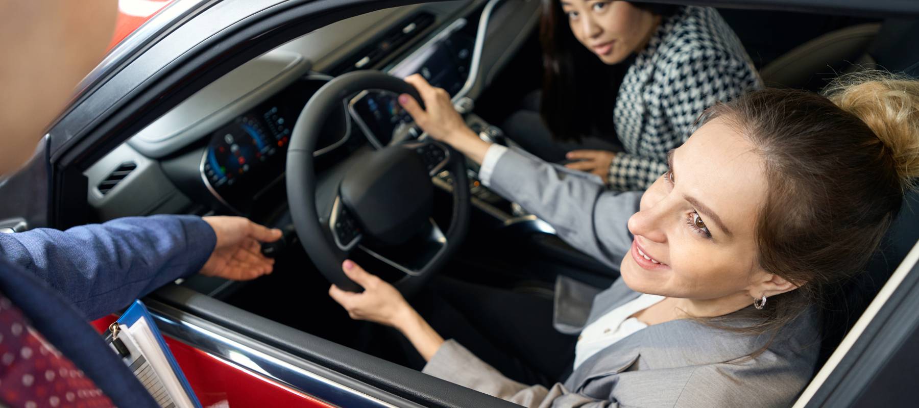 Customers sit inside a car for sale.