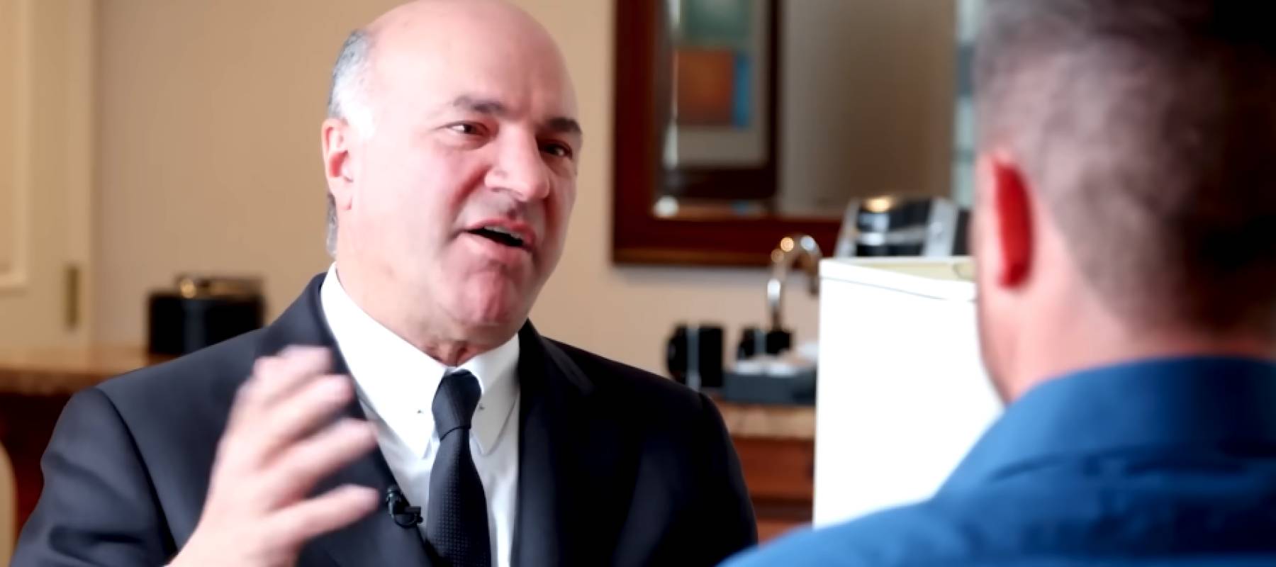 Kevin O'Leary speaking to a man sitting across from him, gesturing.
