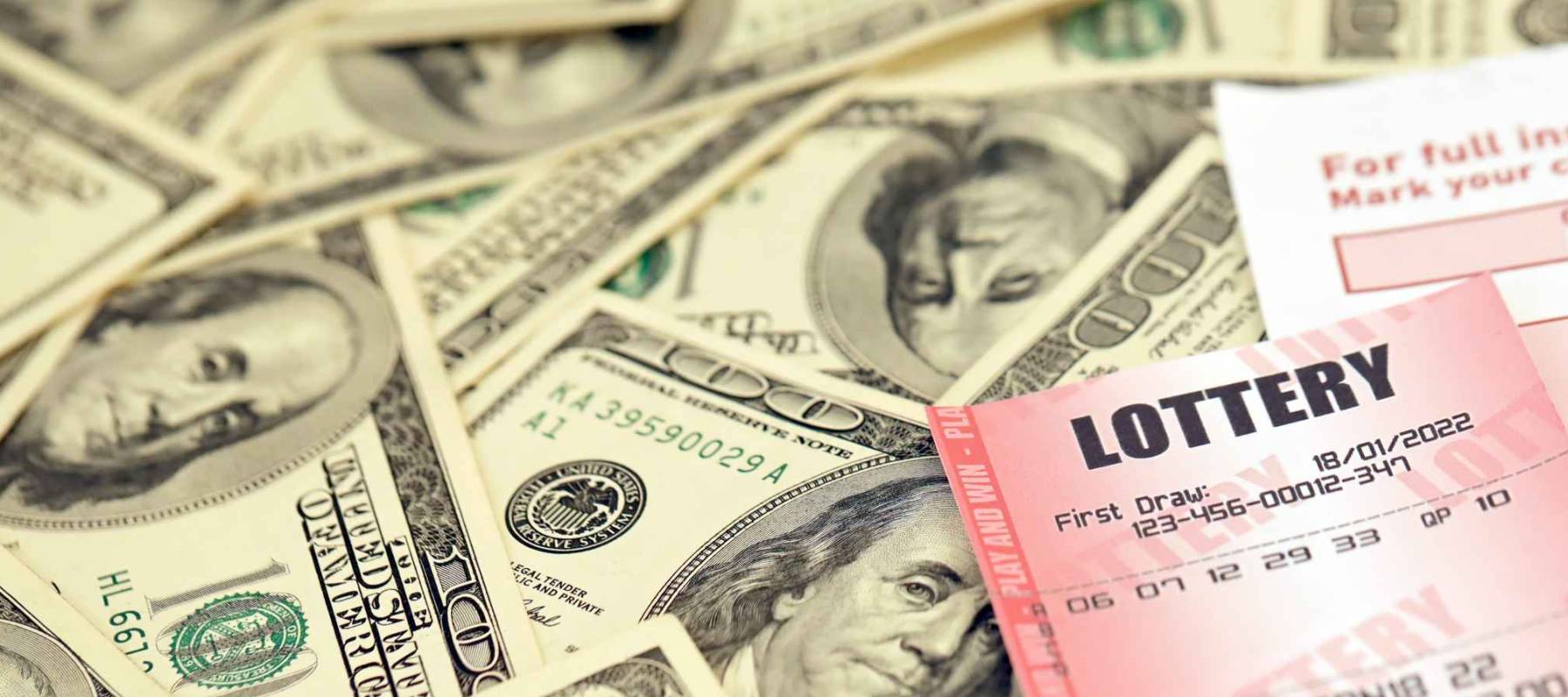 Red lottery ticket lies on pink gambling sheets with numbers for marking on big amount of hundred dollar bills. Lottery playing concept or gambling addiction. Close up photo