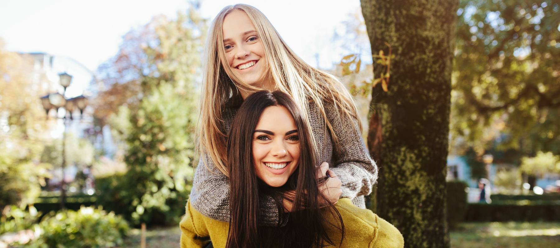 A woman gives her friend a piggyback ride.