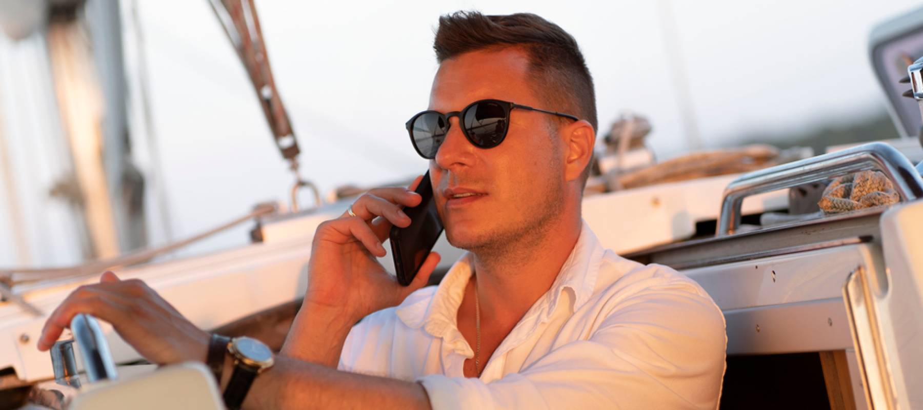 Young millionaire talking on the phone on a yacht.