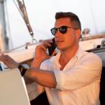 Young millionaire talking on the phone on a yacht.