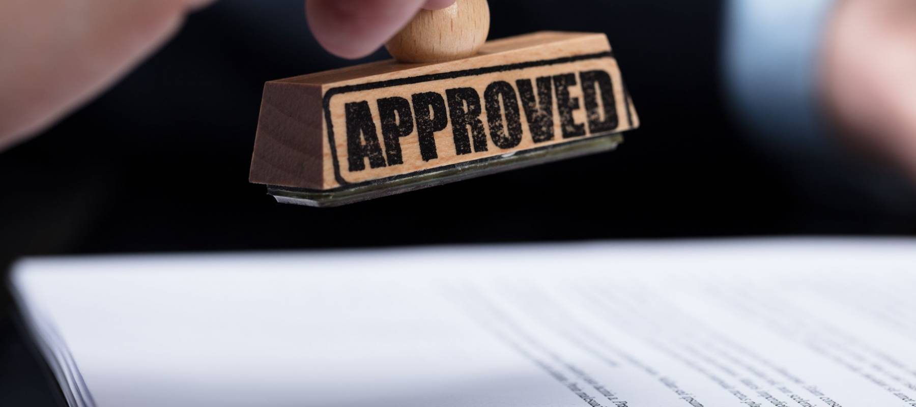 Close-up Of A Businessperson's Hand Stamping On Approved Contract Form
