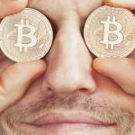 Bearded man holding symbolic bitcoins over his eyes