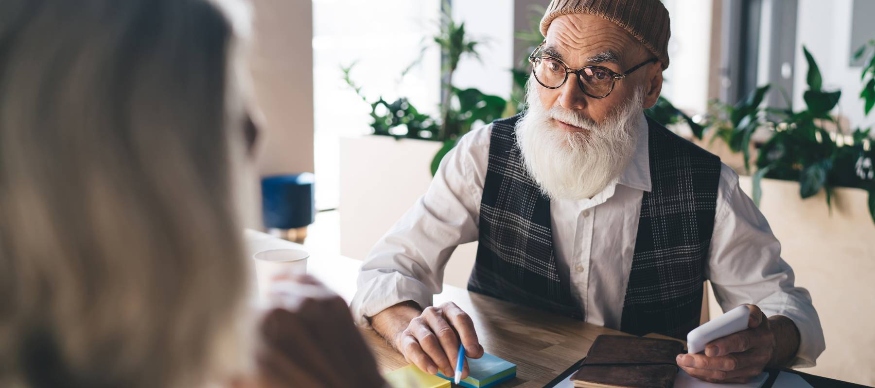 Senior man looking intrigued at what a woman is telling him in an office setting