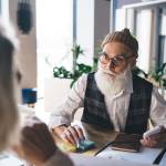 Senior man looking intrigued at what a woman is telling him in an office setting