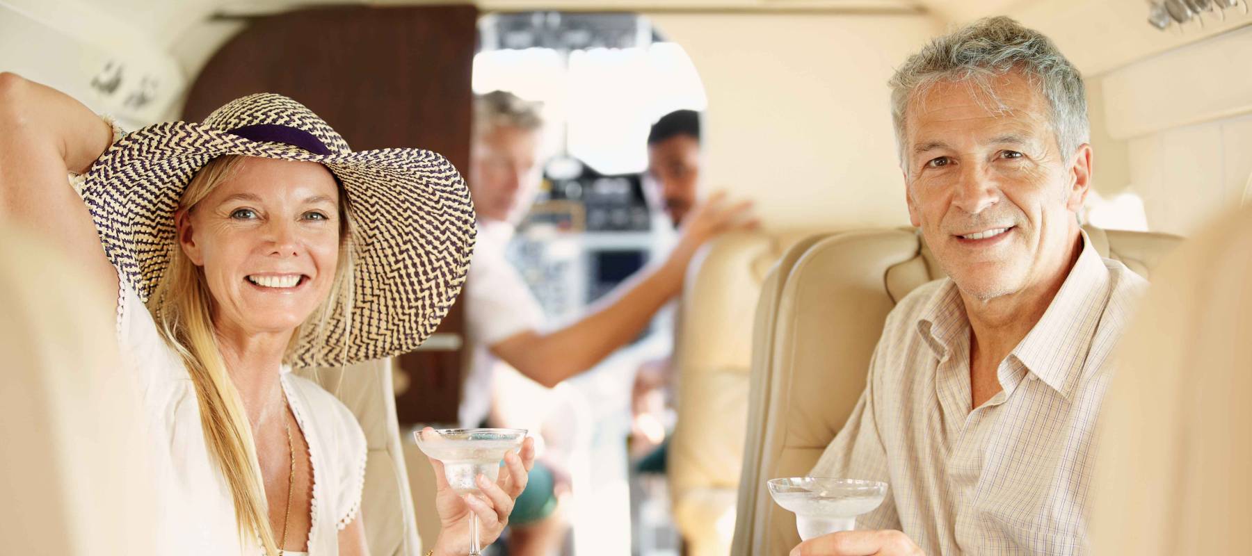 mature couple sitting in the back of a private jet drinking cocktails