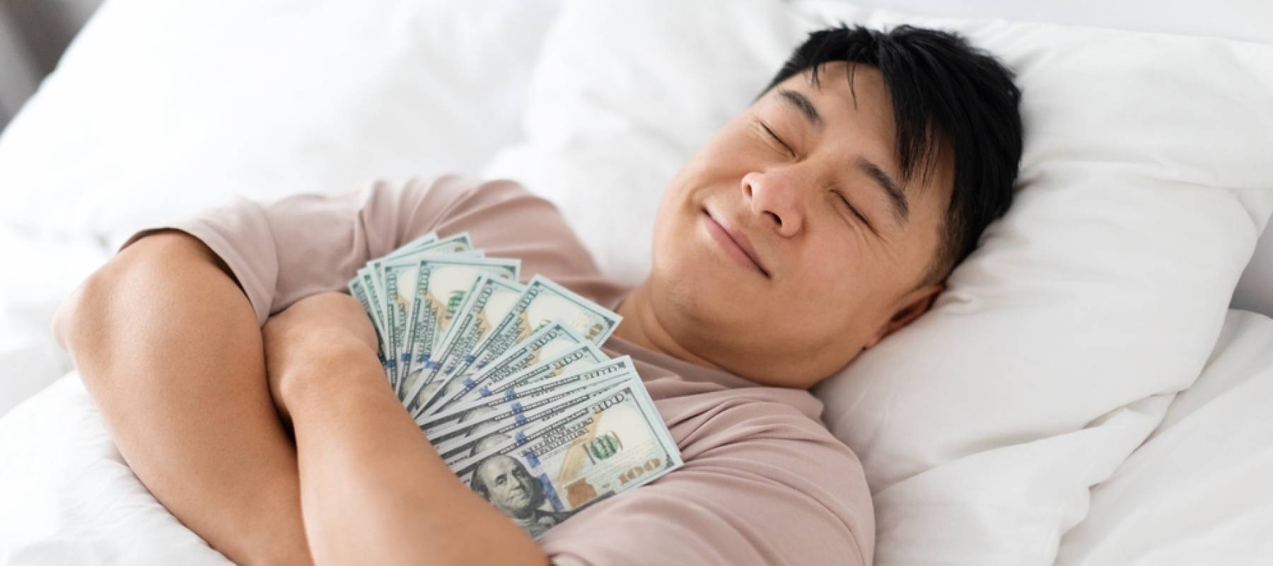 Happy sleeping middle aged chinese man hugging bunch of cash dollars