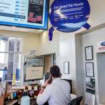 Ford car dealer service manager seen from behind, sitting at his desk on the phone.