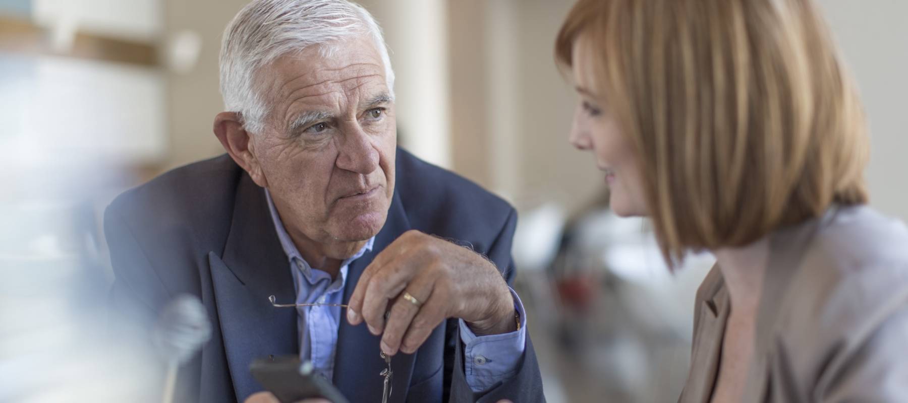 Senior businessman smartphone text to colleague at breakfast table in hotel restaurant