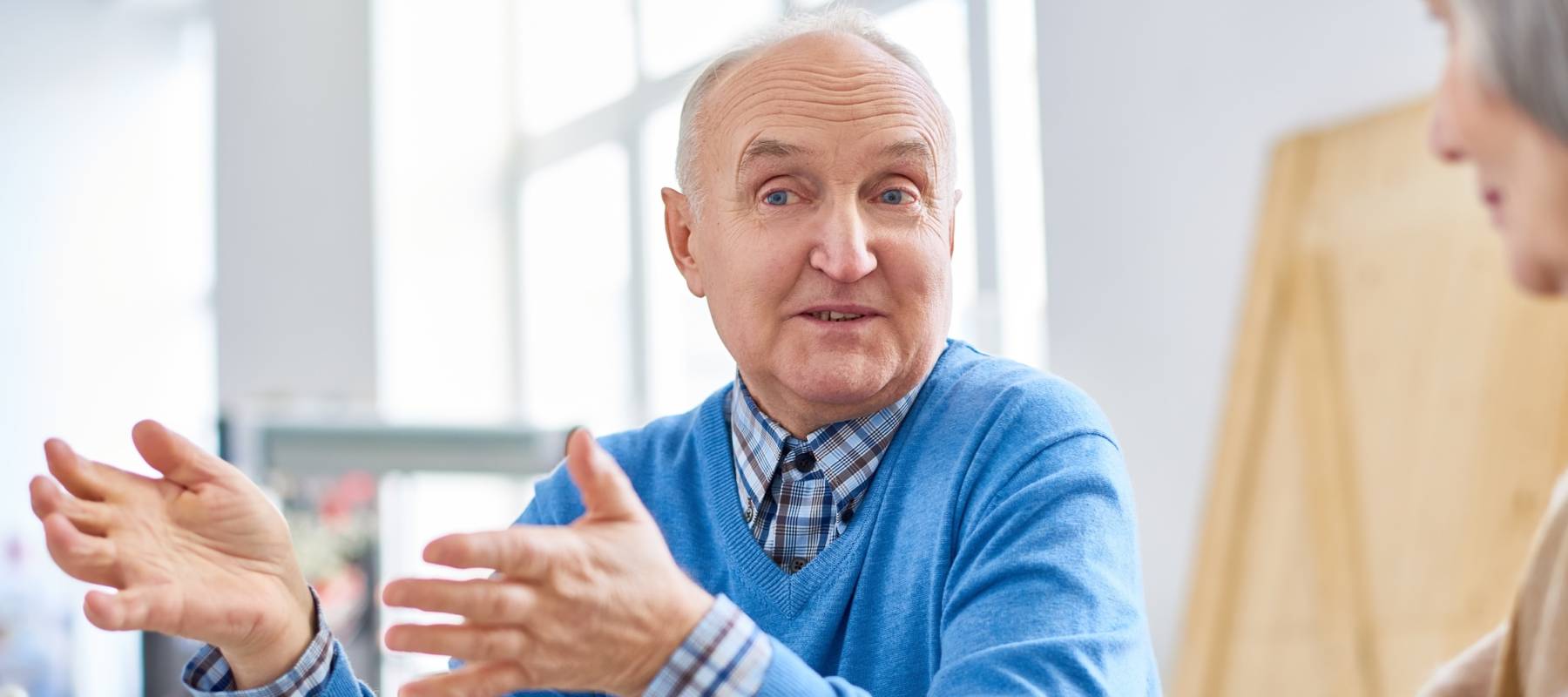 Group of elderly people sitting at table in assisted living home and taking in relaxation while drinking tea.