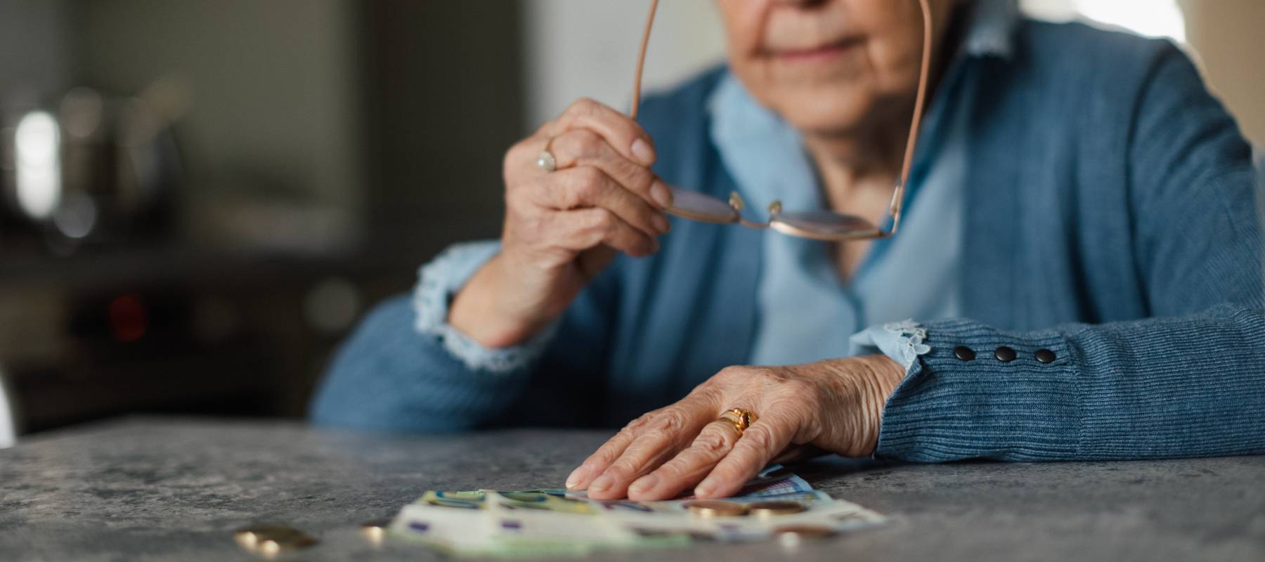 senior Caucasian woman counting money at kitchen table