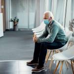 Caucasian senior man with protective face mask sitting in waiting room at the hospital