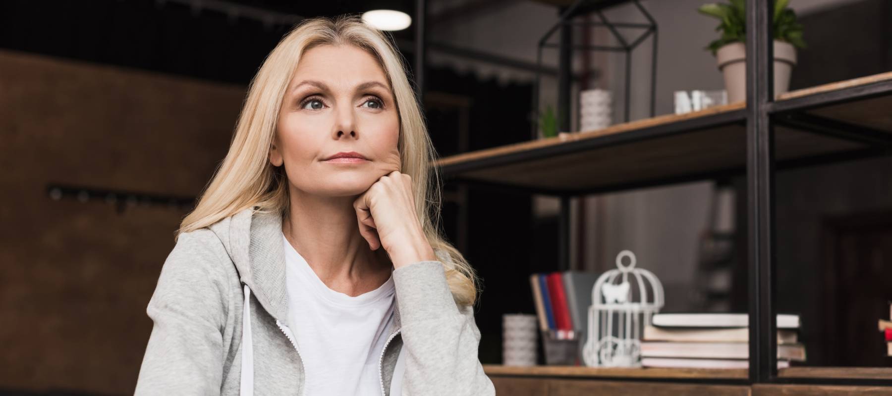 beautiful pensive middle aged woman looking away while sitting at home