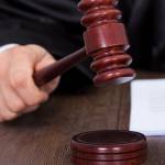 Cropped image of judge giving verdict by hitting mallet at desk