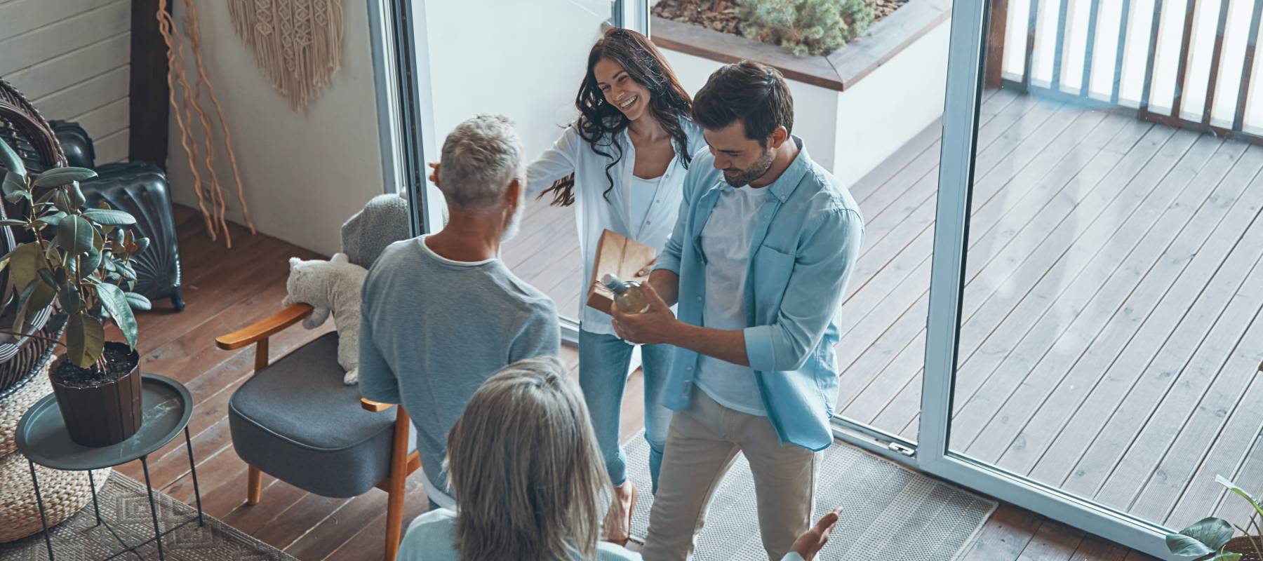 overhead view of happy senior parents meeting young couple inside the house