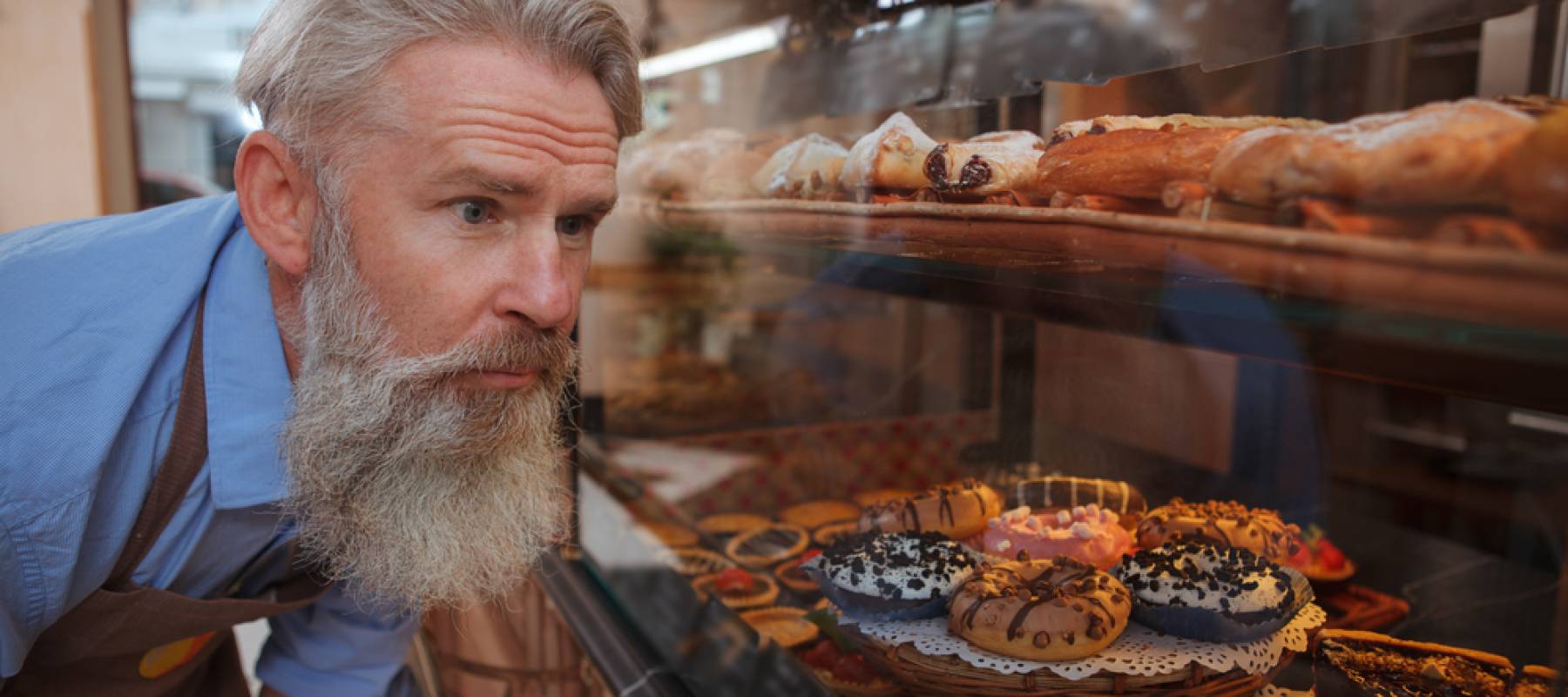Senior baker examining donuts at his bakery store