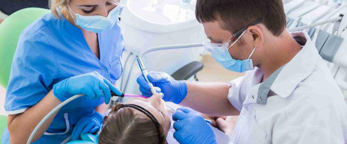 Healthcare, medicine. Young woman with dentist in a dental surgery.