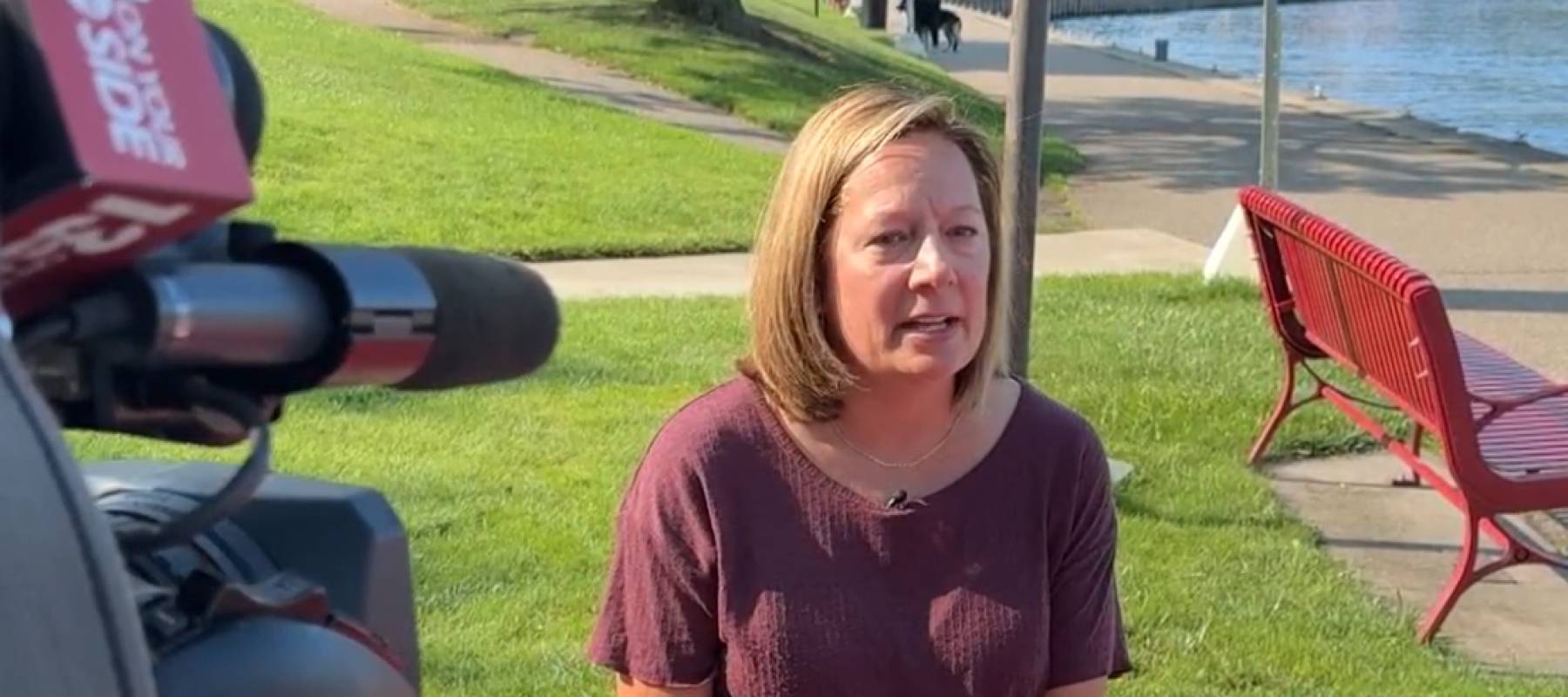 Woman sitting on park bench, seen from above being interviewed by someone sitting across her.