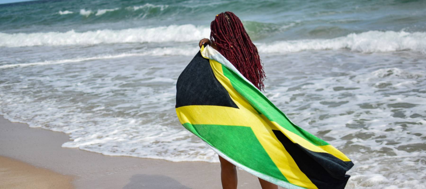 Woman with Jamaican flag walking along beach